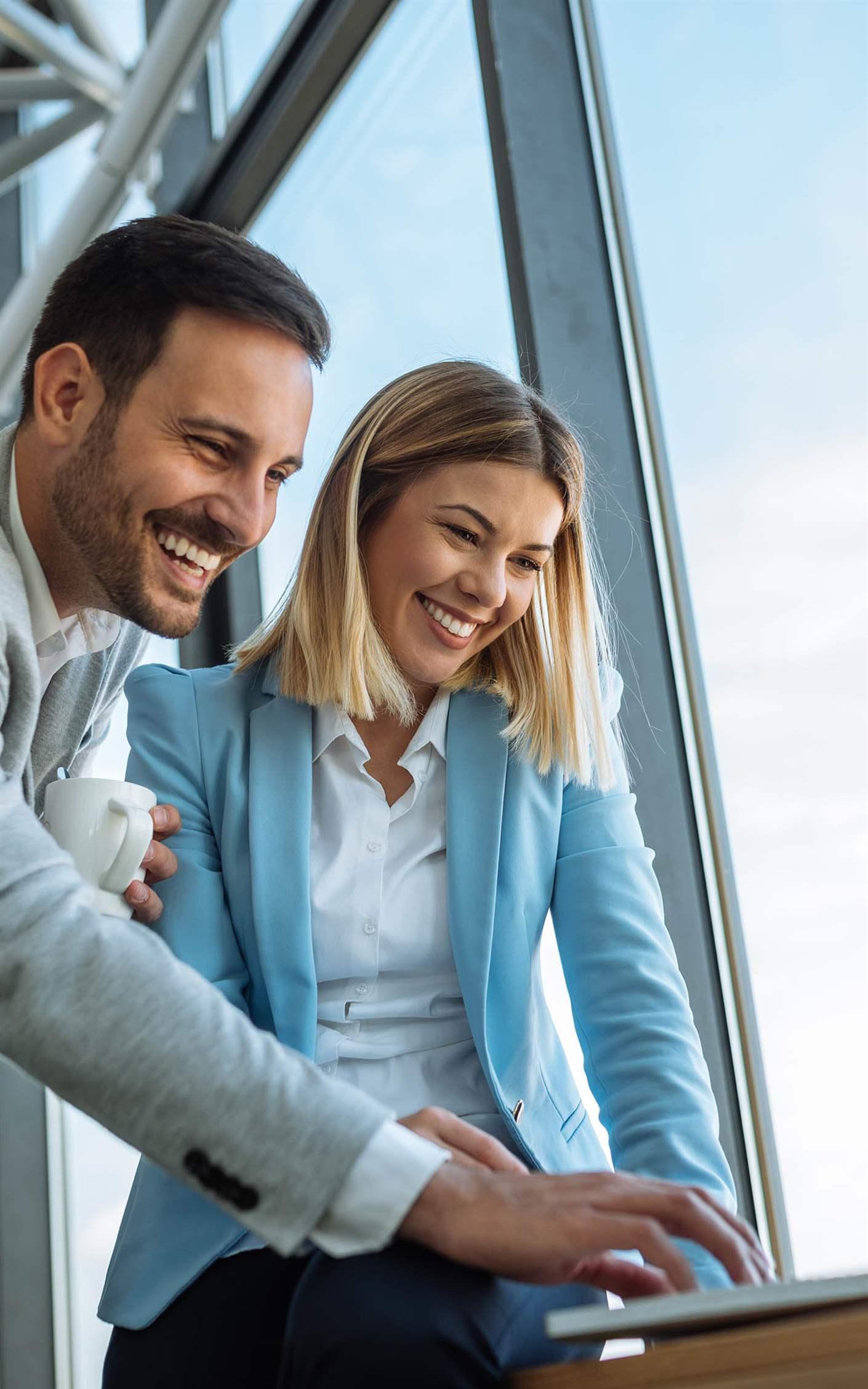 Shot of two happy young businesspeople enjoying working on a laptop.